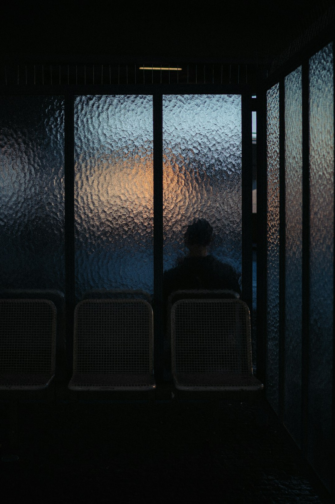 Silhouette of a person typing on a laptop in a dim room